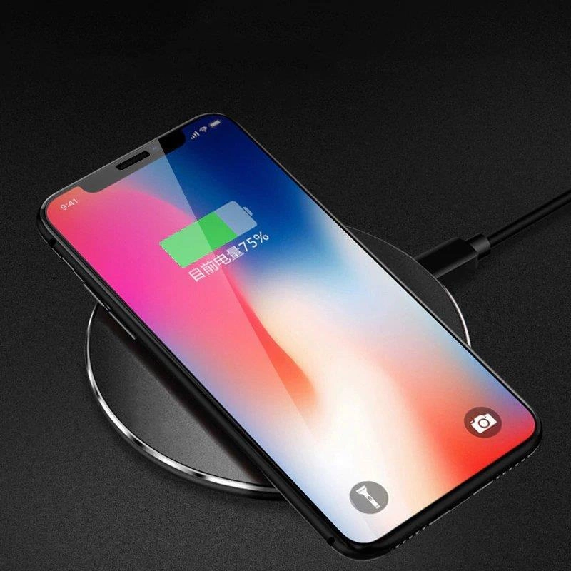 Smartfon z kolorowym wyświetlaczem leży na bezprzewodowej ładowarce, pokazując ikonę baterii z napisem \'75%\'.