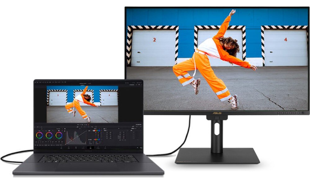 Monitor ASUS wyświetla obraz z laptopa, na którym widać osobę w pomarańczowym stroju skaczącą przed niebieskimi drzwiami z numerem 2. Logo ASUS jest widoczne na dolnej ramce monitora.