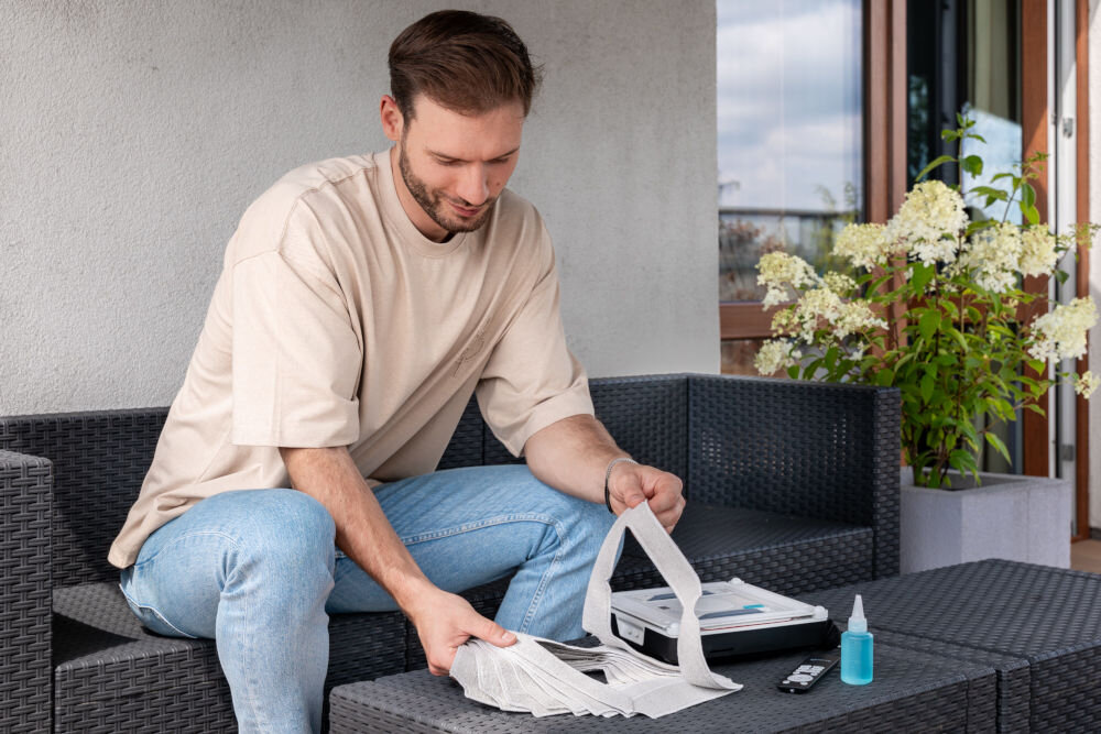 Nakładki SETTI+ do robota do okien WC700 8 szt. uśmiechnieta osoba biorąca jedną z nakładek leżących na stoliku w tle widoczny robot leżący na stole