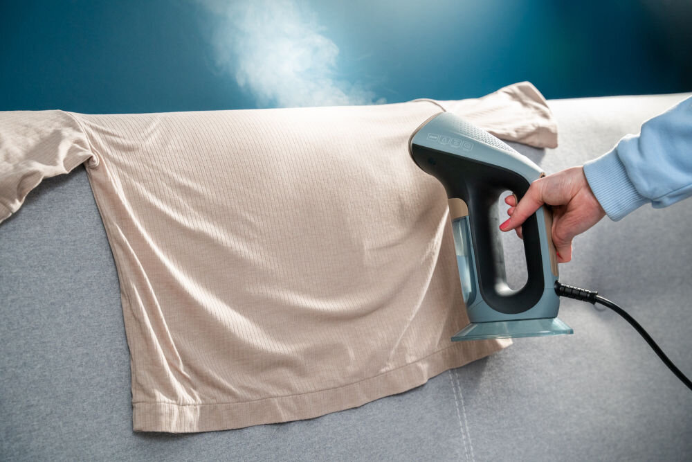 Parownica do ubrań (Steamer) GÖTZE & JENSEN SI800 Parownica do ubrań (Steamer) GÖTZE & JENSEN SI800 prasowanie bluzki leżącej na oparciu kanapy w pionie w poziomie spiczasta końcówka