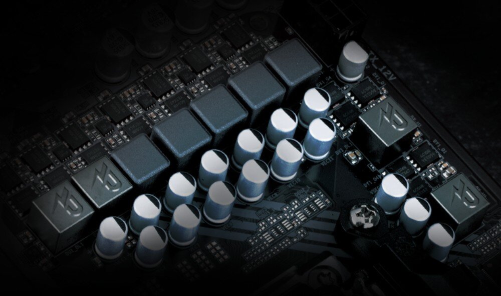 Płyta główna GIGABYTE B650M Gaming WiFi6E Zbliżenie na sekcję zasilania płyty głównej. Widoczne są rzędy ciemnych dławików oraz srebrno-czarnych kondensatorów polimerowych na czarnym laminacie