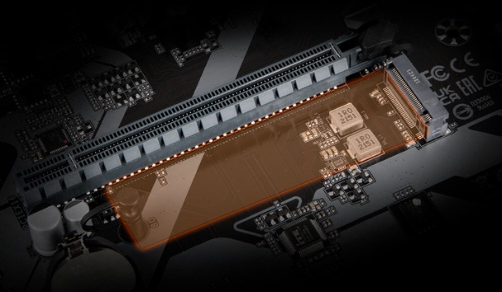 Płyta główna GIGABYTE B650M Gaming WiFi6E Zbliżenie na gniazdo dysku M.2 na płycie głównej, które jest podświetlone pomarańczową poświatą. W tle widać slot PCIe oraz drobne elementy elektroniczne