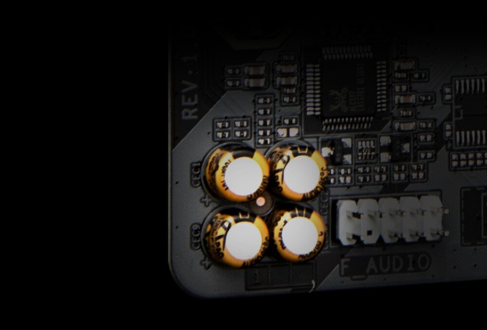 Płyta główna GIGABYTE B650M Gaming WiFi6E Zbliżenie na cztery złote kondensatory sekcji audio umieszczone w rogu czarnego laminatu płyty głównej. Obok widoczny jest napis 'F_AUDIO' oraz układ scalony