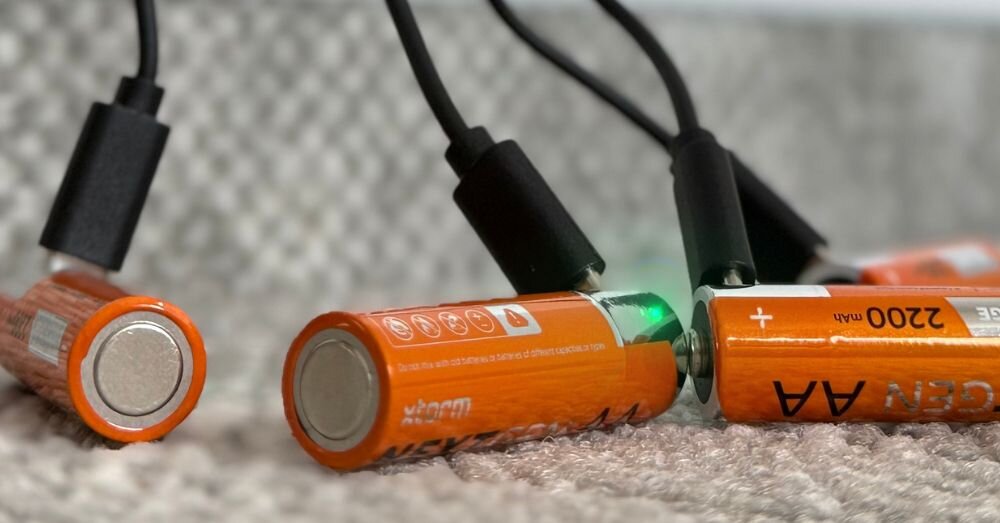 Akumulatorki AA 2200 mAh XTORM XNG2AB4 (4 szt.), port, USB-C, powerbank, biwak, baterie leżą na wykładzine z podpiętymi do nich portami ładowania