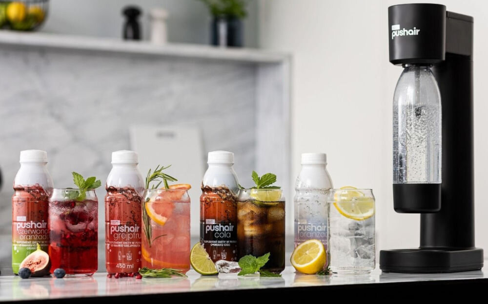 Saturator DAFI PushAir Czarny z dwoma nabojami + butelka czarny saturator stoi na blacie zamontowana butelka z wodą obok stoją smakowe syropy w kolorowych butelkach w walce z nadmiarem plastiku butelka wielokrotnego użytku Funkcja filtracji możliwość przygotowania gazowanych napojów wygoda troska o ekologię dbanie o planetę troszczenie się o swoje zdrowie codzienne nawodnienie 