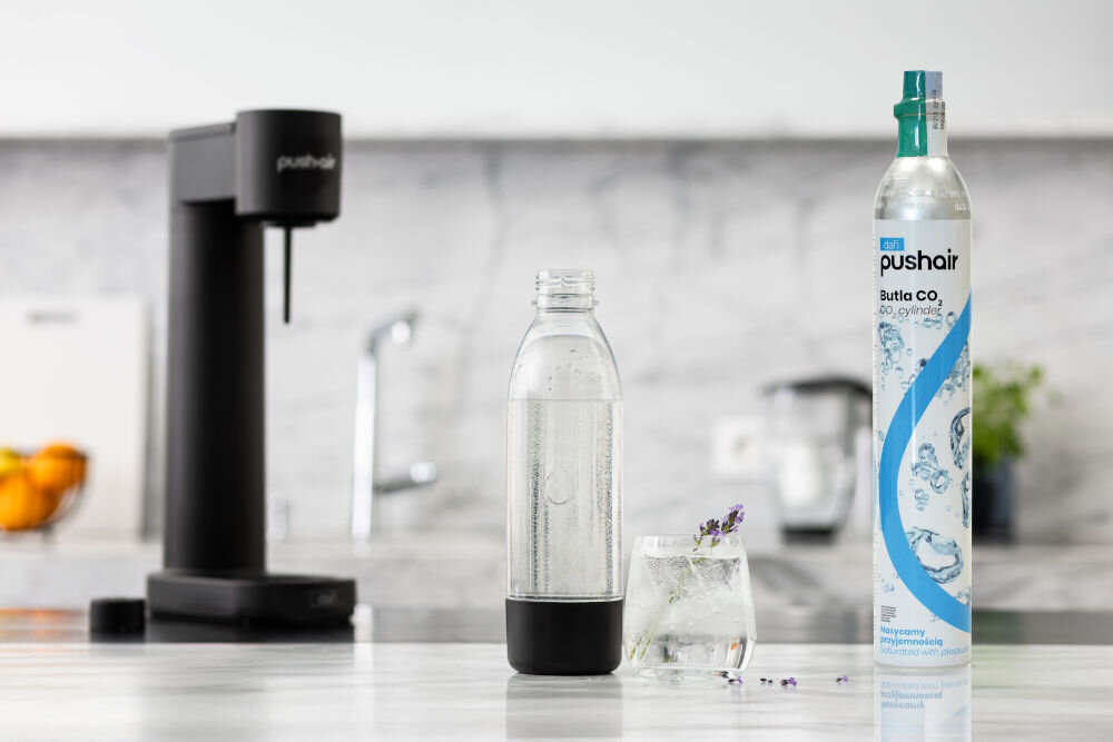 Saturator DAFI PushAir Czarny z dwoma nabojami + butelka czarny saturator butelka z wodą woda gazowana w szklance obok stoi butla z gazem kompaktowe wymiary (430 mm wysokości, 120 mm szerokości, 230 mm głębokości) na każdym blacie kuchennym praktyczność elegancja nie zajmuje zbyt dużo miejsca  