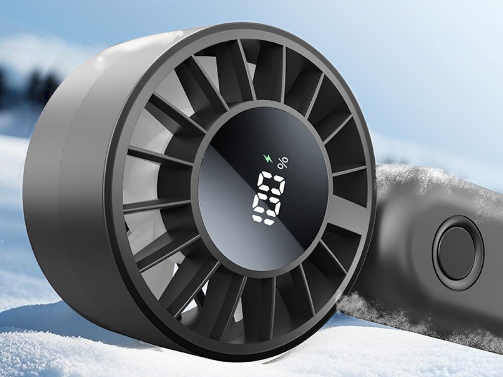 Wentylator USAMS Mini ZB352 5 prędkości nawiewu Zbliżenie na czarny wentylator ręczny z wyświetlaczem LED pokazującym stan naładowania 100%, leżący na puszystym śniegu.