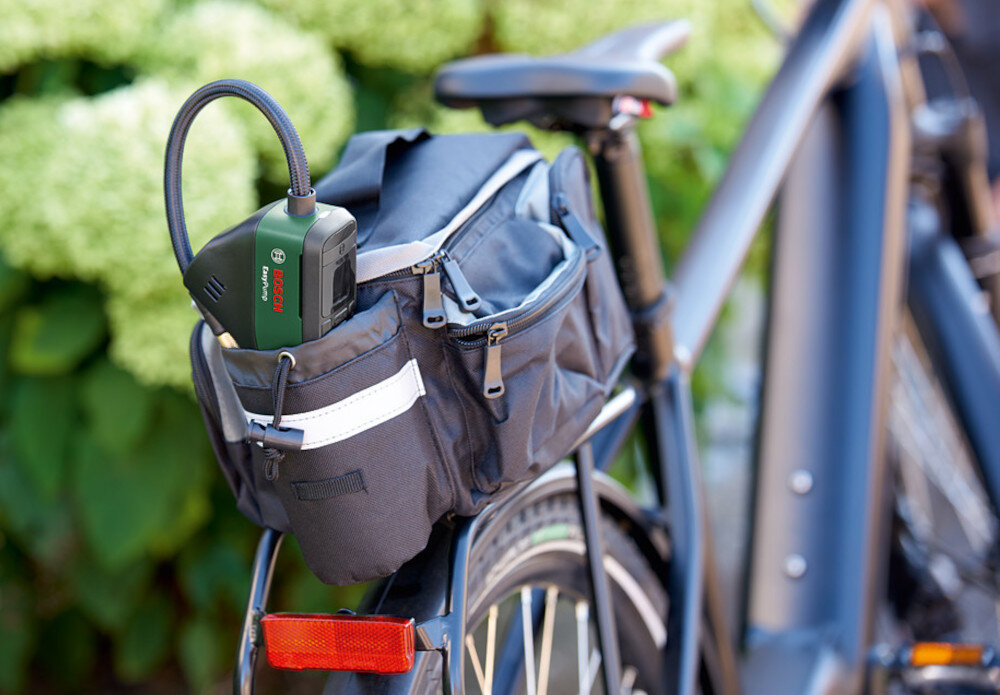 Pompka rowerowa BOSCH EasyPump 2 0603947001 rower pompka umieszczona w torbie rowerowej w tle zielone rośliny precyzyjne pompowanie mobilność łatwa obsługa praktyczne etui w zestawie