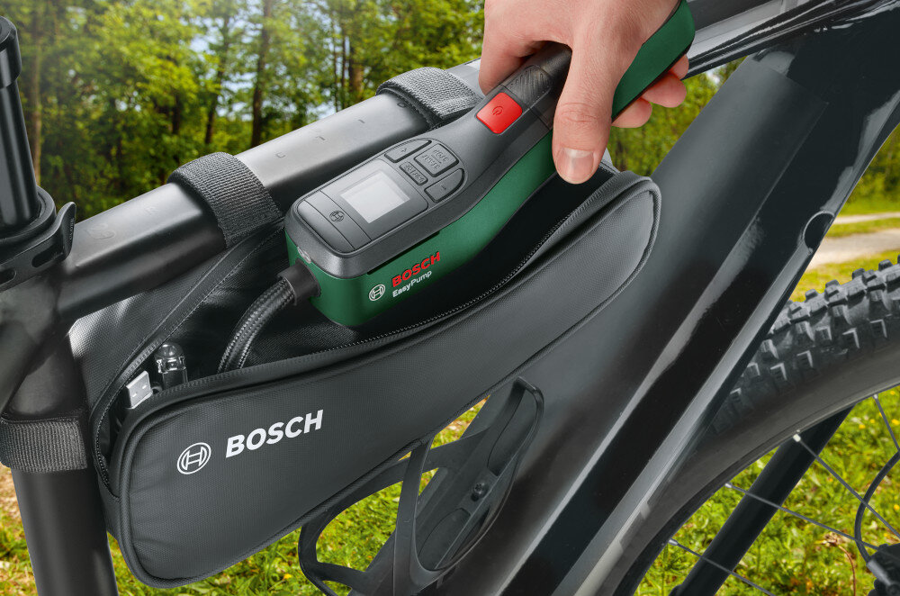 Pompka rowerowa BOSCH EasyPump 2 0603947001 rama rowerowa osoba wyciąga z torby rowerowej pompkę w tle drzewa trawa długość 265 mm szerokość 123 mm wysokość 87 mm waga 0,43 kg łatwa w przechowywaniu i transportowaniu ergonomiczna rękojeść