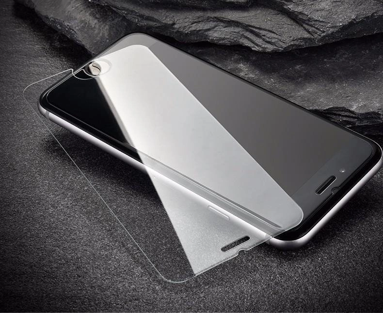 Na obrazie widoczny jest telefon komórkowy z nałożonym szkłem hartowanym, które leży na ekranie urządzenia. Tło jest ciemne, a powierzchnia, na której znajduje się telefon, ma teksturę przypominającą kamień.