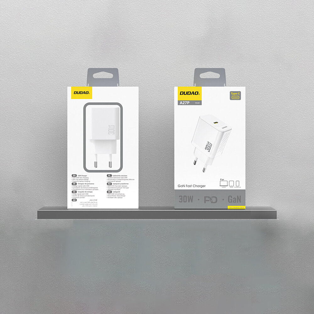 Na obrazie widoczne są dwa opakowania ładowarki sieciowej Dudao A27P 30W Pd GAN USB-C w kolorze białym, umieszczone na półce. Opakowania mają logo Dudao i zawierają ilustracje oraz specyfikacje produktu, takie jak \'30W\', \'PD\', \'GaN\'.