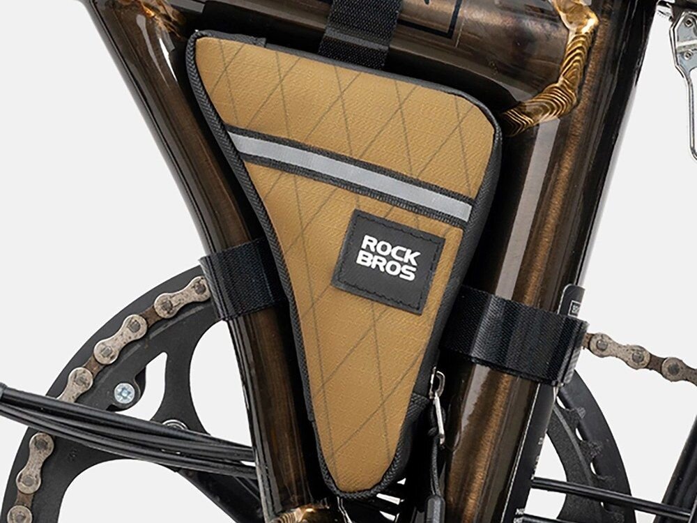 Brązowa torba rowerowa na ramę z logo \'ROCKBROS\', zamocowana na rowerze. Torba ma trójkątny kształt i ozdobiona jest szarym paskiem odblaskowym.