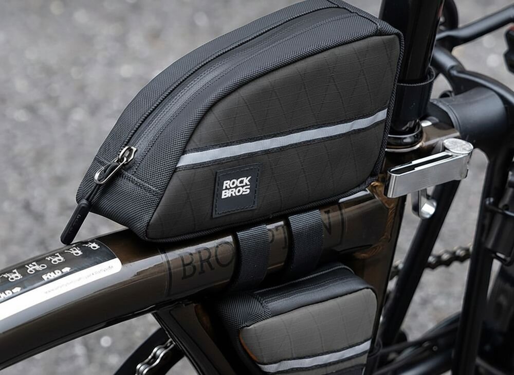 Czarna torba rowerowa zamontowana na ramie roweru z widocznym logo \'ROCKBROS\'. Torba ma zamek błyskawiczny i odblaskowy pasek.