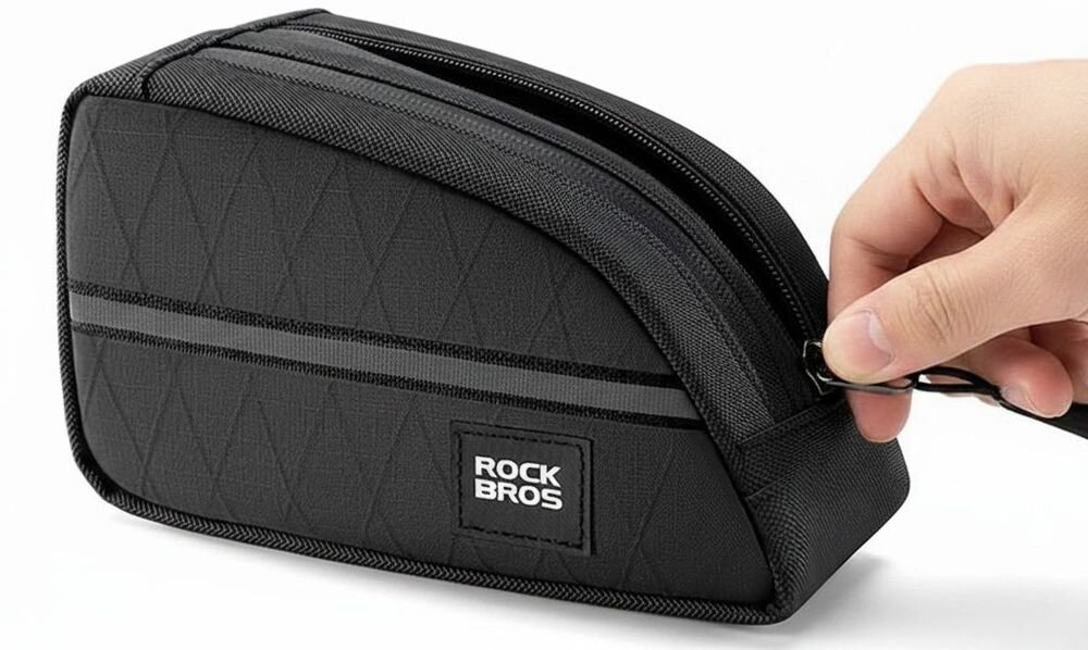 Czarna torba rowerowa z zamkiem błyskawicznym, na której widnieje logo \'ROCKBROS\'. Ręka trzyma suwak zamka, otwierając torbę.