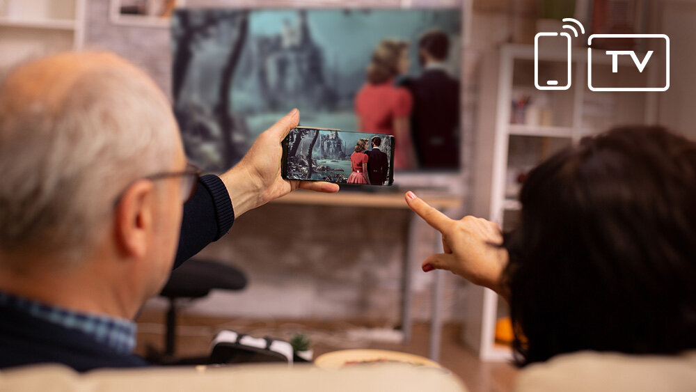 Telewizor JVC LT-32VQF550D - Bezprzewodowe udostępnianie, meżczyzna trzymający telefon w ręku z uruchomionym udostępnianiem ekranu na telewizor