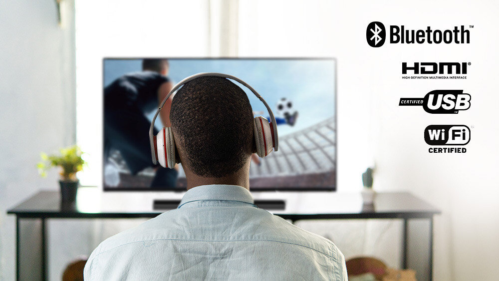 Telewizor JVC LT-32VQF550D - HDMI z ARC i Bluetooth, mężczyzna oglądający program w telewizji z nałożonymi słuchawkami, Dwa złącza HDMI, ARC, USB-A, Internet 