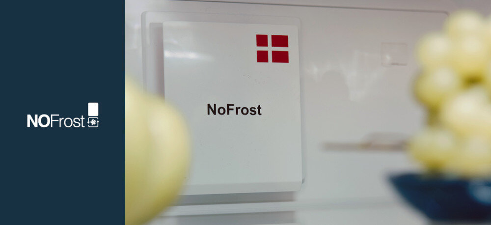 Obraz przedstawia wnętrze zamrażarki z widocznym napisem \'NoFrost\' oraz czerwonym symbolem składającym się z czterech kwadratów. Po lewej stronie na ciemnym tle znajduje się napis \'NOFrost\' z ikoną zamrażarki.
