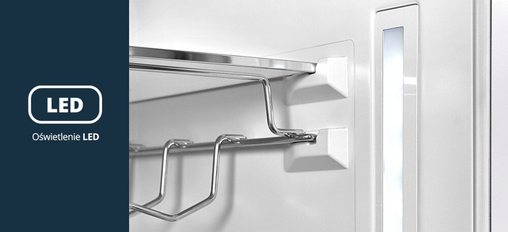 LODÓWKA VESTFROST VR-BF27953H0S Na zdjęciu przedstawiono wnętrze lodówki z metalową półką i uchwytem na butelki, oświetlone wąskim, pionowym panelem LED umieszczonym na bocznej ścianie. Po lewej stronie, na granatowym tle, widnieje napis „LED” oraz podpis „Oświetlenie LED”, podkreślający jasne i energooszczędne doświetlenie wnętrza chłodziarki oświetlenie LED lodówka dobra widoczność energooszczędność brak nagrzewania wnętrza