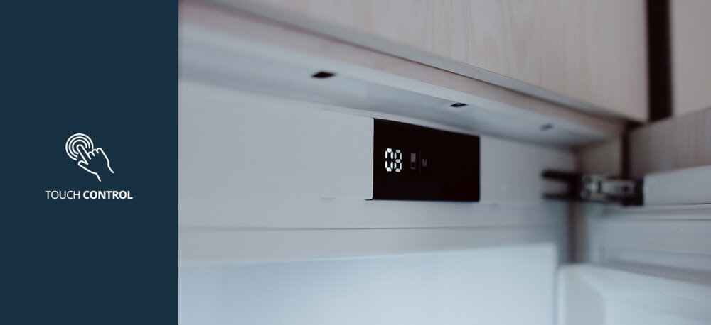 LODÓWKA VESTFROST VR-BF27953H0S Na zdjęciu pokazano górną część wnętrza lodówki z eleganckim, czarnym panelem sterowania z wyświetlaczem LED umieszczonym pod szafką. Po lewej stronie, na granatowym tle, znajduje się piktogram dotyku oraz napis „TOUCH CONTROL”, podkreślający wygodne, dotykowe sterowanie temperaturą i funkcjami urządzenia Touch Control panel dotykowy wentylator Turbo cicha praca 36 dB energooszczędna lodówka 89 kWh zawiasy nożycowe zabudowa