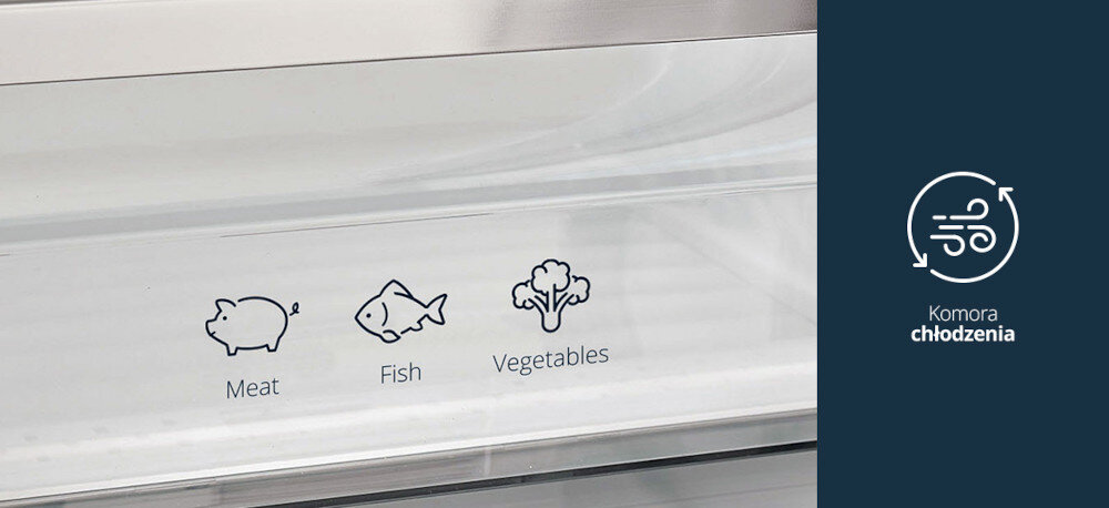 Lodówka VESTFROST VR-FB383-3H0B Na zdjęciu pokazano szufladę w lodówce oznaczoną piktogramami mięsa, ryby i warzyw, przeznaczoną do ich przechowywania w optymalnych warunkach. Po prawej stronie, na granatowym tle, widnieje ikona cyrkulacji powietrza z napisem „Komora chłodzenia”, podkreślająca funkcję strefy intensywnego chłodzenia. komora niska temperatura mięso ryby sery świeżość bez zamrażania
