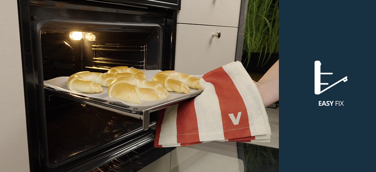 Piekarnik VESTFROST VO-65W19MAVMC Pokazuje wyjmowanie blachy z upieczonymi rogalikami z piekarnika Vestfrost, demonstrując wygodne prowadnice Easy Fix easy fix prowadnice teleskopowe wygodne wysuwanie blach piekarnik prowadnice