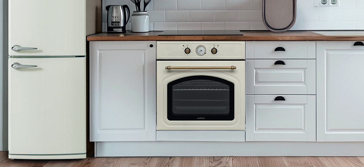 Piekarnik VESTFROST VO-65W19MAVMC Przedstawia jasną kuchnię z piekarnikiem Vestfrost zamontowanym w szafce, obok retro lodówki w dopasowanym stylu retro matowa czerń chromowane detale styl vintage piekarnik design