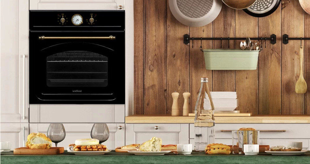 Piekarnik VESTFROST VO-65W19MAVMB Kuchnia z jasnymi szafkami, drewnianym akcentem i zabudowanym piekarnikiem Vestfrost sprzyja wspólnym posiłkom. Na stole widoczny jest wybór świeżych potraw, co podkreśla rodzinny i przytulny klimat wnętrza retro do zabudowy elektryczny czarny matowy styl retro w kuchni vestfrost retro design do kuchni vintage