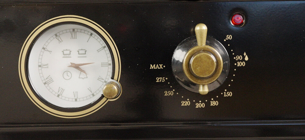 Piekarnik VESTFROST VO-65W19MAVMB Na zdjęciu znajduje się klasyczny panel sterowania piekarnika z analogowym zegarem i stylowym pokrętłem do regulacji temperatury. Skala umożliwia ustawienie temperatury w zakresie od 50 do 275°C, a całość podkreśla retro charakter urządzenia zegar analogowy z zegarem mechanicznym klasyczny design retro z pokrętłami precyzyjne sterowanie czasem pieczenia