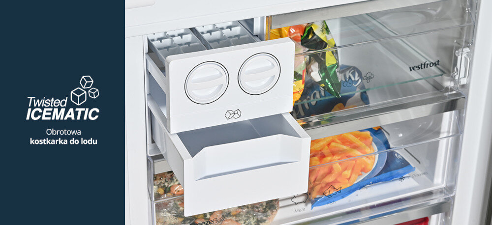 LODÓWKA VESTFROST VR-FB492-3H0B Na zdjęciu wnętrza zamrażarki widać wysuwaną, obrotową kostkarkę do lodu Twisted Icematic z białym pojemnikiem na kostki. Po lewej stronie, na granatowym tle, umieszczono logo „Twisted ICEMATIC” oraz napis „Obrotowa kostkarka do lodu”, a za kostkarką widoczne są przezroczyste szuflady z mrożonkami Twisted IceMatic Kostkarka kostki lodu chłodne napoje lód