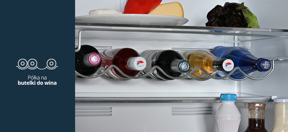 Lodówka VESTFROST VR-FB492-3H0B Na zdjęciu z prawej strony widać szklane i plastikowe butelki z napojami ułożone poziomo na metalowej, falistej półce na butelki wewnątrz lodówki. Po lewej stronie, na granatowym tle, znajduje się ikonka trzech butelek oraz napis „Półka na butelki do wina”, podkreślający funkcję dedykowanego uchwytu półka na wino przechowywanie poziome stabilność butelki porządek elegancki design