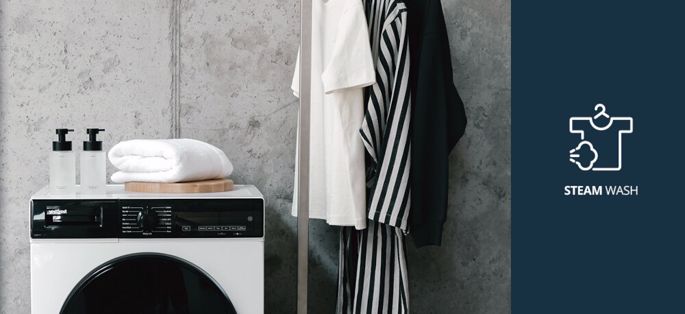 Pralka VESTFROST VW-FW4B1270EU Na zdjęciu pokazano pralkę marki Vestfrost z lustrem i złożonymi ręcznikami na górze, ustawioną w stylowym, minimalistycznym wnętrzu. Po prawej stronie grafika informuje o funkcji STEAM WASH (pranie parowe), którą oferuje ten model pralki Steam Wash pranie parowe para wodna mniej zagnieceń higiena prania świeże ubrania alergeny
