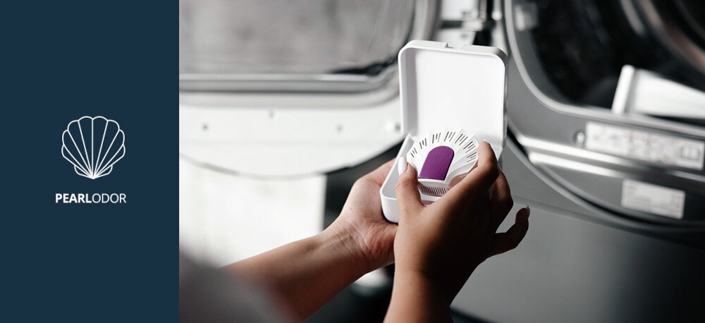 Suszarka VESTFROST VT-FD42HN90EU Na zdjęciu widoczne są dłonie osoby trzymającej pojemnik z wkładką zapachową Pearl Odor do suszarki Vestfrost, na tle otwartych drzwiczek urządzenia. Po prawej stronie znajduje się grafika informująca o systemie odświeżania bębna suszarki Pearl Odor PearlOdor wkład zapachowy świeży zapach ubrań zapach podczas suszenia odświeżanie tkanin Vestfrost zapach ubrań