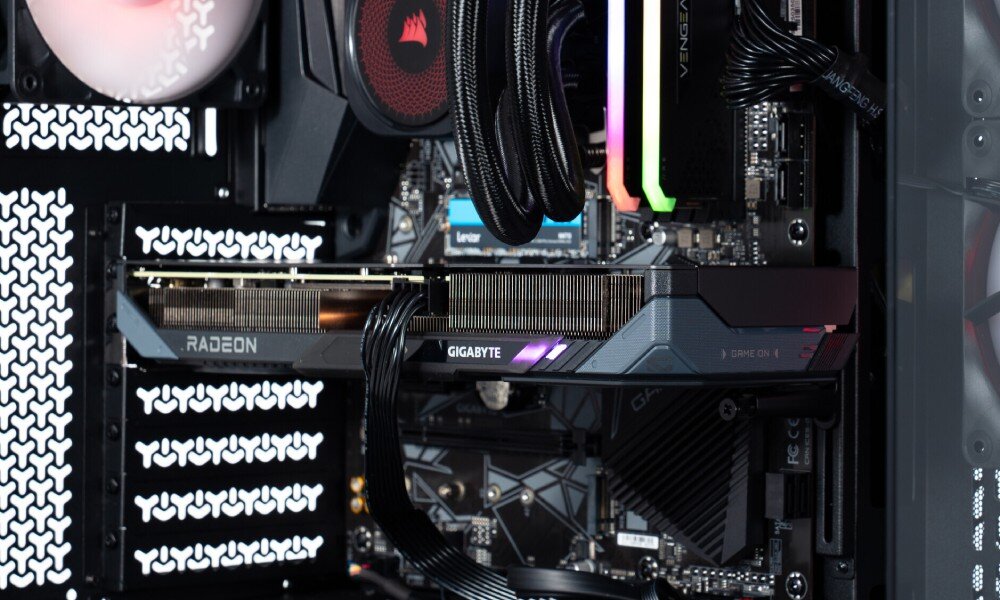 Komputer OPTIMUS E-Sport GB550T-CR7 detal środkowej części wnętrza komputera przedstawiający kartę graficzną z napisem 'Gigabyte' i 'Radeon' zamontowaną poziomo nad czarną płytą główną, karta graficzna, wydajność