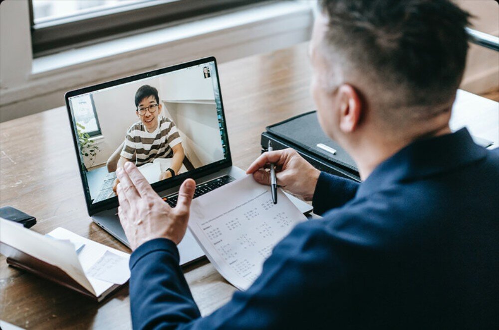 Router TP-LINK Archer BE700 Mężczyzna w biurze prowadzący wideorozmowę na laptopie z widocznym rozmówcą na ekranie