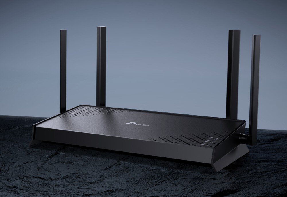 Router TP-LINK Archer BE220 Czarne urządzenie sieciowe z czterema antenami stojące na ciemnej, chropowatej powierzchni przypominającej kamień, opis