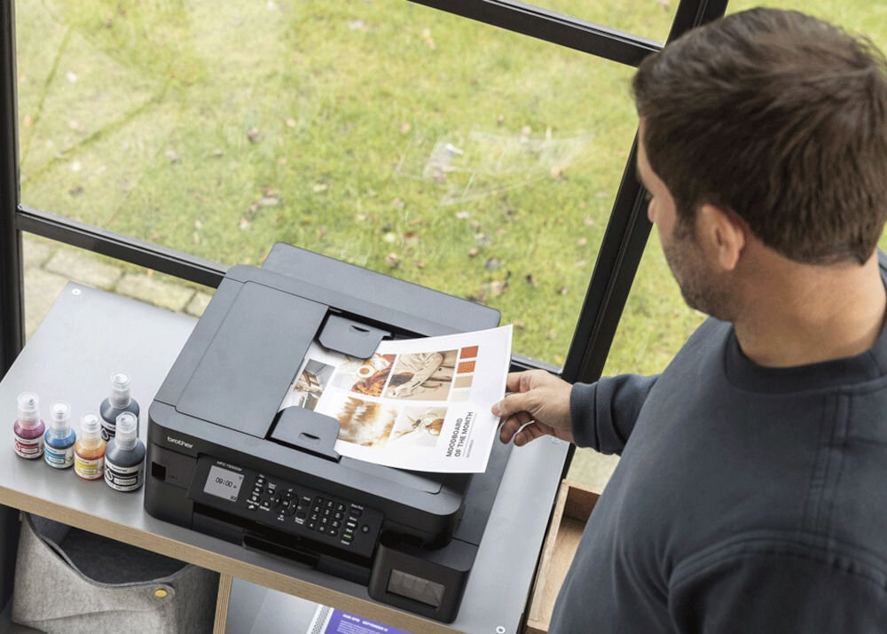 Urządzenie wielofunkcyjne BROTHER MFC-T930DW Druk w kolorze, Automatyczny druk dwustronny, Wi-Fi mężczyzna stojący przy urządzeniu i trzymający kartkę rozdzielczość skanowania w kolorze dokumenty zdjęcia rozdzielczość interpolowana wysoka jakość