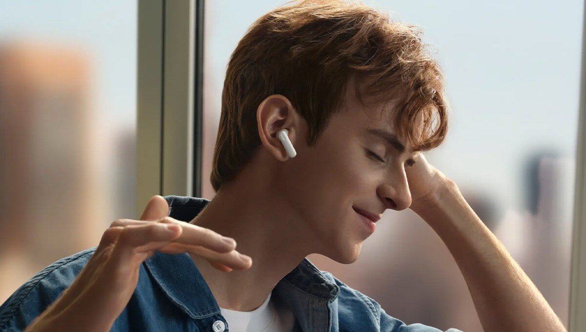 OPPO Enco Buds 3 wszechstronna muzyka, OPPO Alive Audio, Enco Master, 3 profile dźwięku, Młody chłopak przy oknie słuchający muzyki przez słuchawki OPPO Enco Buds3