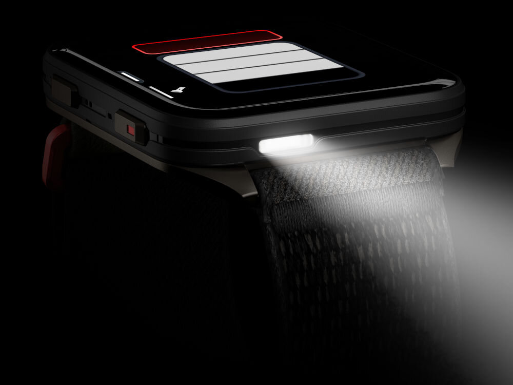 Smartwatch GARMIN Venu X1 Zbliżenie na smartwatch z włączoną latarką rzucającą jasne światło na ciemny pasek. Na ekranie widoczna jest ikona baterii z niskim stanem naładowania. Tło jest ciemne.