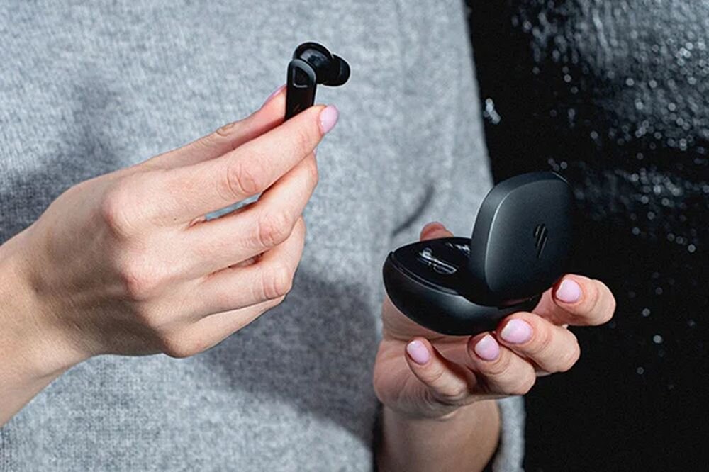 EDIFIER NeoBuds Pro 3 ANC, Wide-Band Multi-Channel ANC, 6 mikrofonów, redukcja hałasu do -50 dB, osoba trzymająca słuchawkę oraz etui w rękach