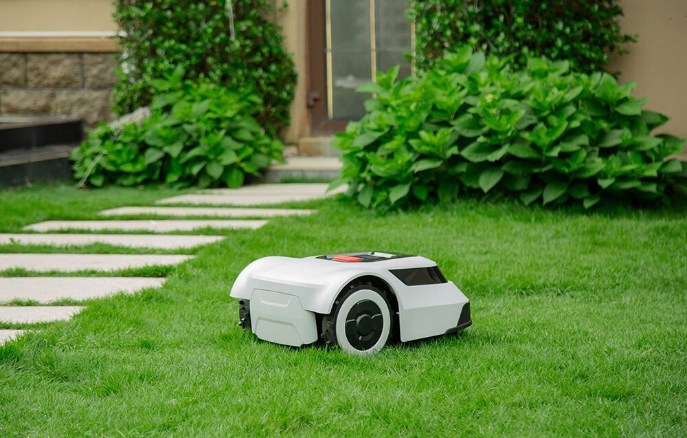 Robot koszący ANTHBOT Pion 1000 robot na trawniku w tle dom rośliny chodnik prędkość koszenia do 90 m² na godzinę prędkość trzykrotnie wyższa technologia tic-tac-toe unika powtarzania tych samych tras równomierne przycinanie całej powierzchni trawnika