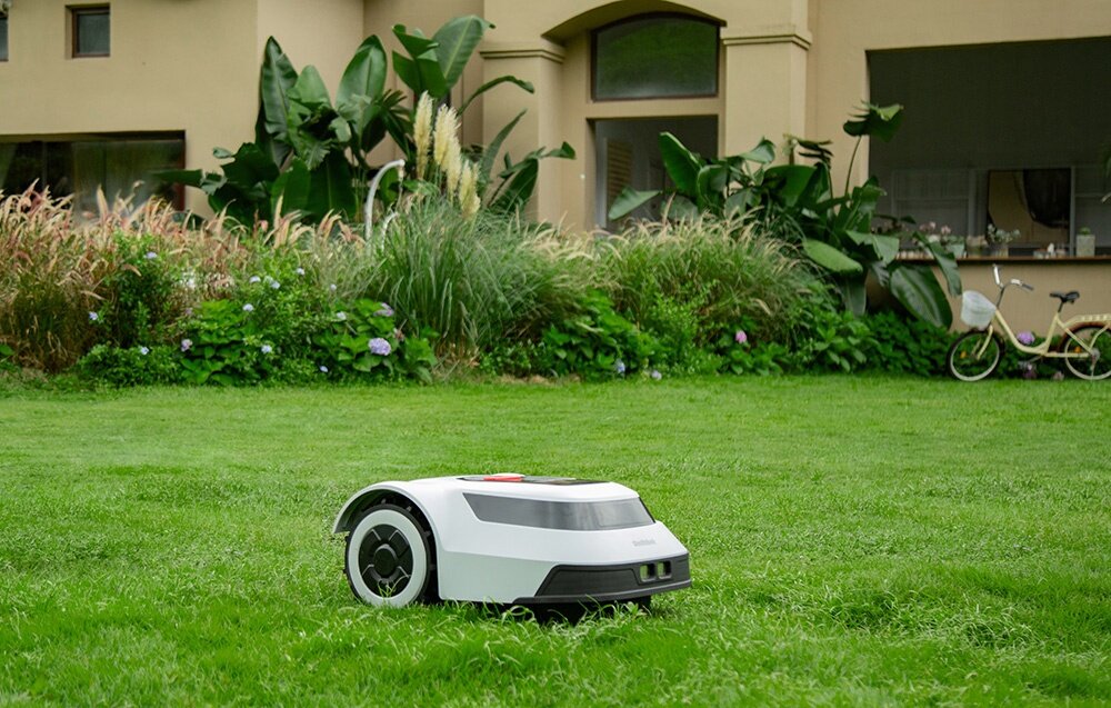 Robot koszący ANTHBOT Pion 1000 robot na trawniku w tle dom rośliny rower samodzielnie wracaja do stacji ładującej czas ładowania około 80 minut automatycznie powraca do pracy wznawia koszenie w miejscu, w którym je przerwał do ogrodów o powierzchni do 1000 m² czas pracy do 70 minut na jednym cyklu ładowania
