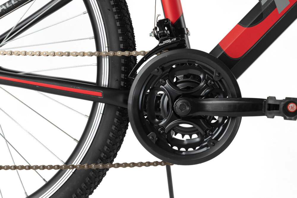 Rower młodzieżowy TRAIL 600 Stal 26 cali dla chłopca Czarno-czerwony zbliżenie na korbę korba marki TRAIL zintegrowana z praktyczną osłoną chroni łańcuch i ubrania podczas jazdy napęd współpracuje z wolnobiegiem POWER o zakresie 14-28 zębów płynna zmiana biegów optymalne przełożenia wysoka trwałość stabilna praca komfort użytkowania