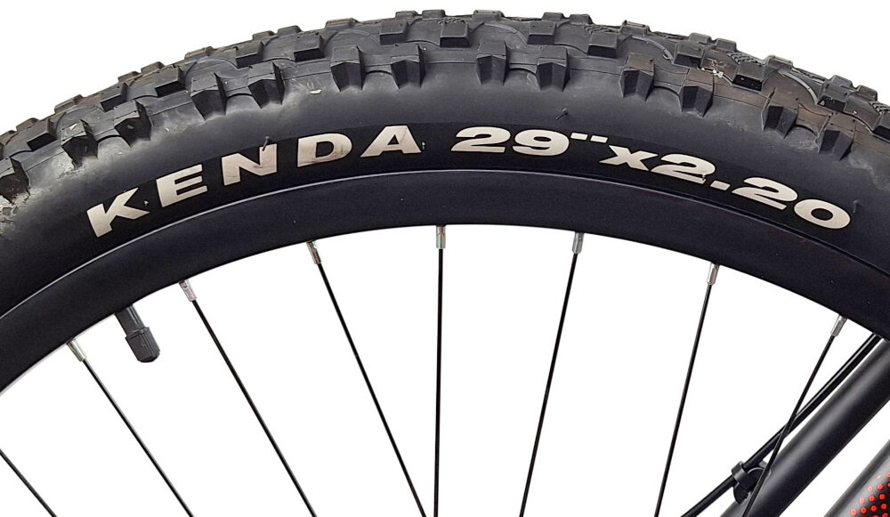 Rower górski MTB INDIANA X-Pulser 1.9 M21 29 cali męski Czarno-Czerwony zbliżenie na oponę rozmiar koła 29 cali łatwe pokonywanie przeszkód duży kontakt koła z podłożem szerokie opony marki KENDA dobra przyczepność aluminiowe obręcze zachowanie regularnego kształtu kół stabilne trzymanie opony bezpieczna i komfortowa jazda regularne sprawdzanie ciśnienia powietrza wartość na bocznej części opony