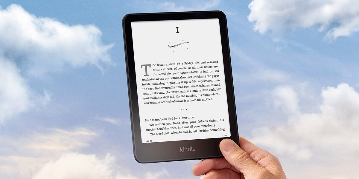 Osoba trzyma czytnik e-booków z wyświetlonym tekstem na ekranie. Na dole urządzenia widoczne jest logo \'kindle\'.