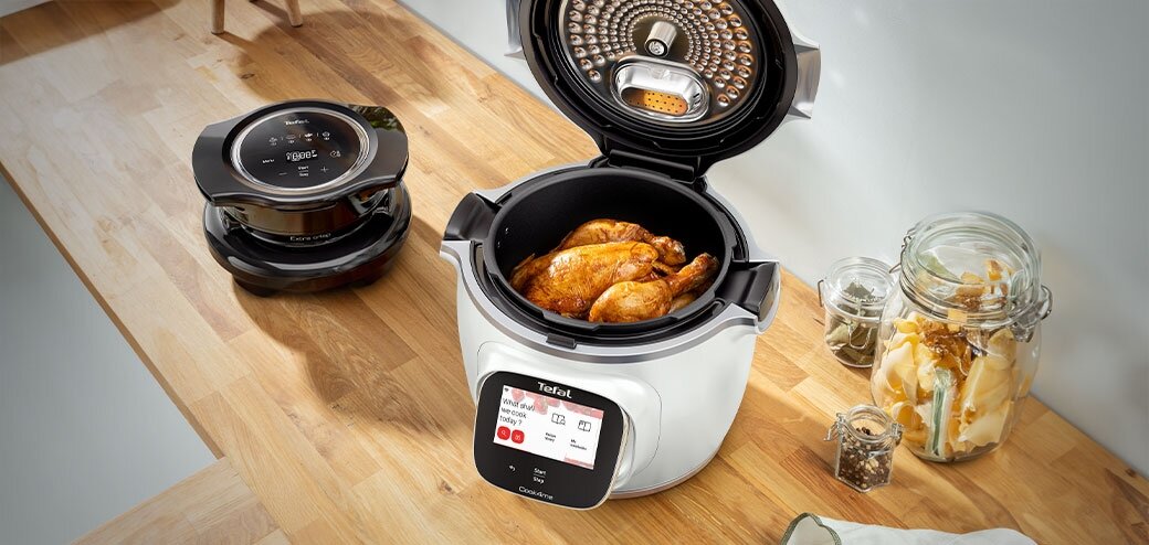 Cook4me Touch Pro na kuchennym blacie. Przy nim mężczyzna trzymający pokrywę.