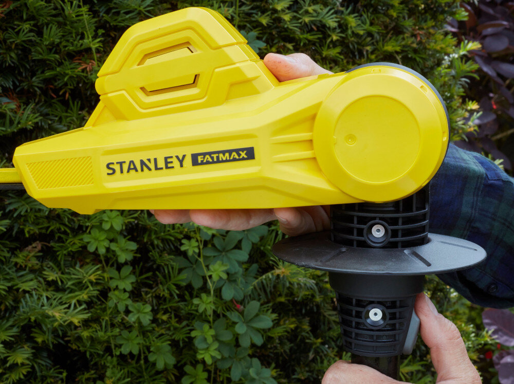Nożyce do żywopłotu STANLEY Fatmax SFMCPH845B-XJ 450mm 18V akumulatorowe zbliżenia na głowicę osoba trzyma głowicę w dłoniach w tle ściana żywopłotu silnik bezszczotkowy dłuższą praca na jednym ładowaniu stabilne obroty pod obciążeniem płynniejsze cięcie grubych gałęzi mniejsze straty energii