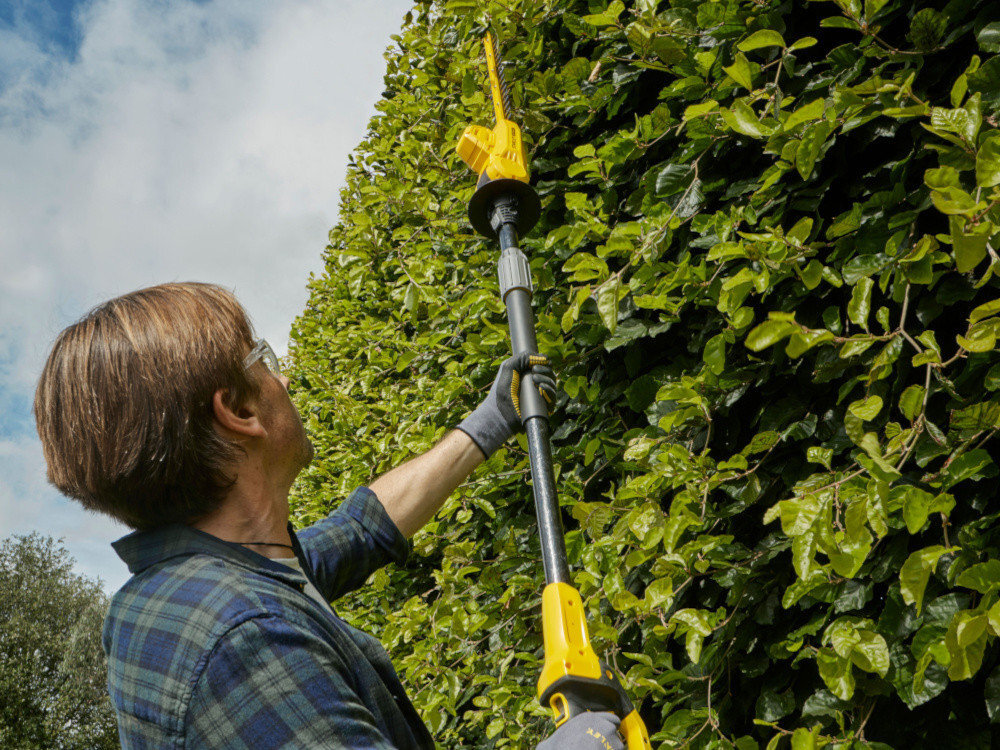 Nożyce do żywopłotu STANLEY Fatmax SFMCPH845B-XJ 450mm 18V akumulatorowe ogród osoba widoczna od tyłu tnie żywopłot częstotliwość skoków do 1400 skoków na minutę równy rytm cięcia stałe tempo pracy ułatwia kontrolę narzędzia użytkownik pracuje spokojniej z lepszą przewidywalnością efektu większą pewnością