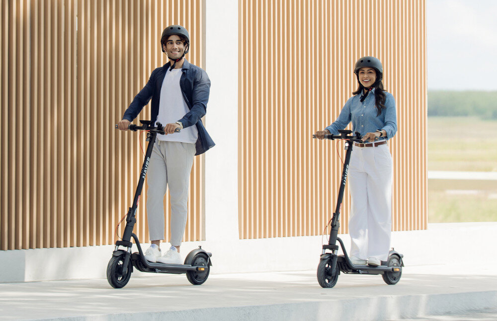 Hulajnoga elektryczna NAVEE V25i Pro 2 20km 300W 10 cali Czarny miasto park droga dwie osoby w kaskach jadą na hulajnogach po drodze hulajnoga elektryczna do jazdy po mieście dynamiczne i ekscytując podróżowanie szereg udogodnień i praktycznych rozwiązań moduł Bluetooth kierunkowskazy składana konstrukcja styl moc wygoda