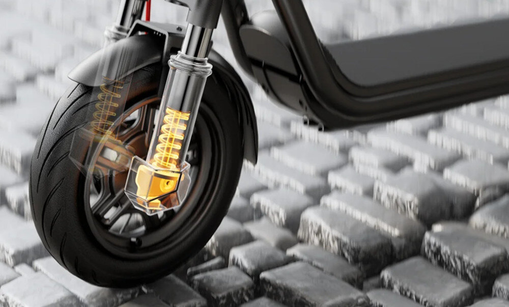 Hulajnoga elektryczna NAVEE V25i Pro 2 20km 300W 10 cali Czarny miasto chodnik bruk zbliżenie na przednie koło na złoto podświetlony widelec przedni widelec z 28 mm skokiem amortyzacji redukuje wstrząsy i nierówności jazda płynna i komfortowa minimalizuje drgania od podłoża stabilna kontrolowana pozycja