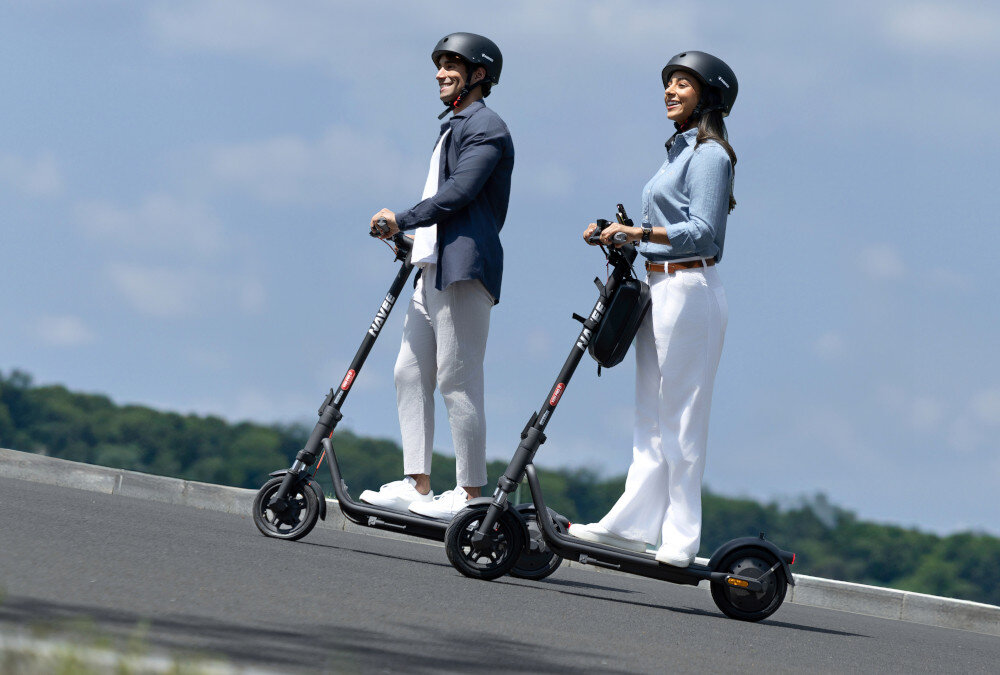 Hulajnoga elektryczna NAVEE V25i Pro 2 20km 300W 10 cali Czarny miasto park droga dwie osoby w kaskach jadą na hulajnogach po drodze pod górkę silnik o mocy 300 W moc szczytowa 600 W cicha praca płynna kontrola prędkości hulajnoga jest w stanie pokonać wzniesienia o nachyleniu do 15% maksymalna prędkość hulajnogi wynosi do 20 km/h